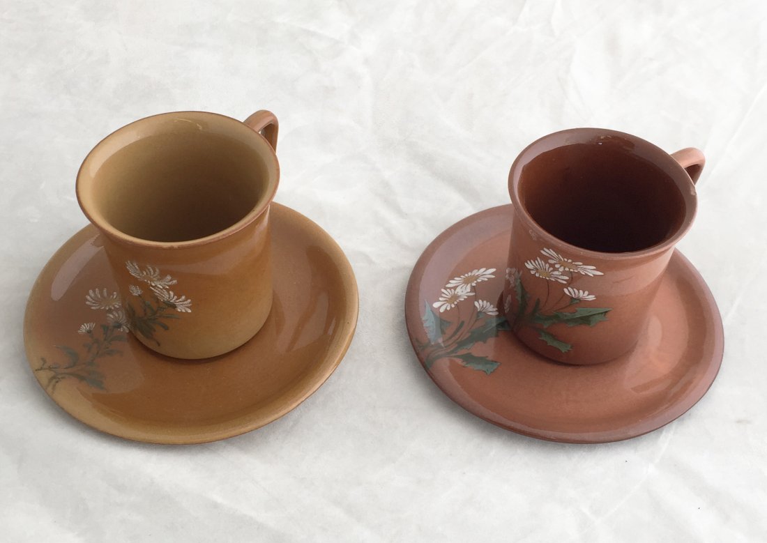 (2) Harriett E. Wilcox Rookwood Cups and Saucers: Including: (1) Date: 1920s. Artist: Harriett E. Wilcox. Cup marked: W/R & HEW and saucer marked: 291/R & HEW. Deep brown with white dandelion design. (1) Date: 1920s. Artist: Harriett E. Wilcox. Cup m