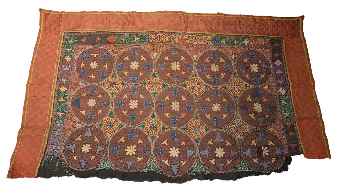 EMBROIDERED SAYMA OR YURT HANGING: An embroidered sayma or yurt hanging with black ground, decorated with fifteen medallions within a floral field, followed by a wide, red border on three sides. Origin: Tajikistan, Central Asia; C. 20t