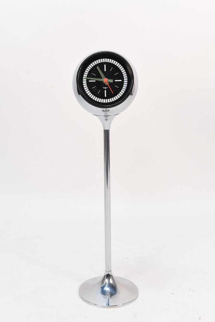HOWARD MILLER CHROME PEDESTAL ORB CLOCK: Dimensions: H 30.25" x W 8.25" x D 6.25" Condition: Battery operated. Functional. Wear consistent with age and use. Second's hand is loose.