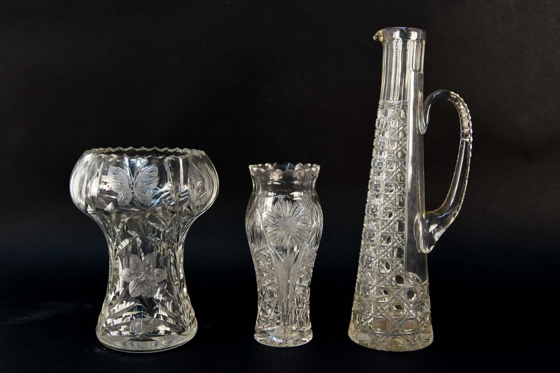 GROUPING OF CUT GLASS: Two vases and one pitcher. Dimensions: (Largest) H 12.75" x W 4.25" x D 3.5" Condition: Very small flea bite near spout of pitcher. Few small chips to vases.