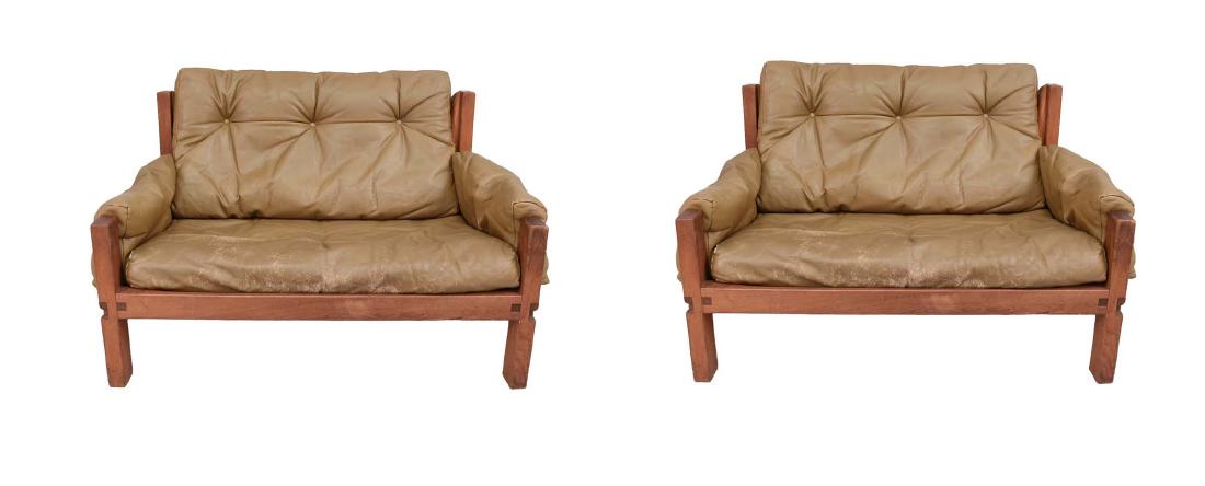 PAIR OF SAFARI STYLE LEATHER & WOOD LOVESEATS: In the style of Arne Norell. Patent numbers on the rubber supports dating to 1969. No upholstery labels. Dimension: H 31" x W 48" x D 30" Condition: Some wear to leather cushions, including tape marks