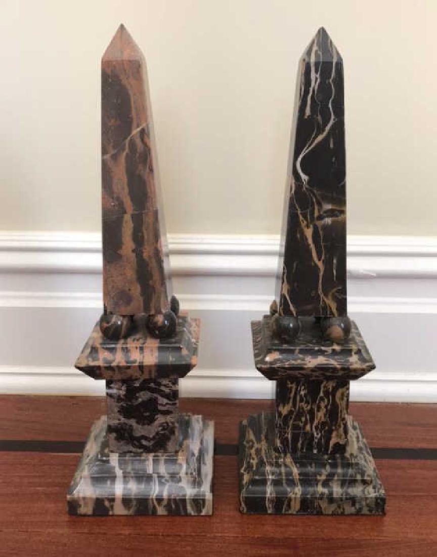 PAIR OF MARBLE OBELISKS ON PILLARS: The pair are carved from marble and feature tapering bodies raised on square stepped bases. Dimensions: H 15"x W 4.75" x D 4.75" Condition: Some chips and cracks