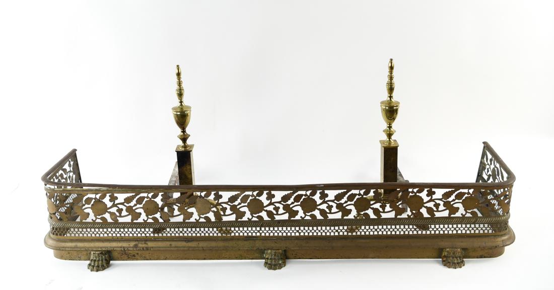 PIERCED BRASS FIRE FENDER AND ANDIRONS: Dimensions: (Fender) H 8.25" x W 48.75" x D 13" Condition: Andirons loose on bases. Tarnish. Wear consistent with age and use.
