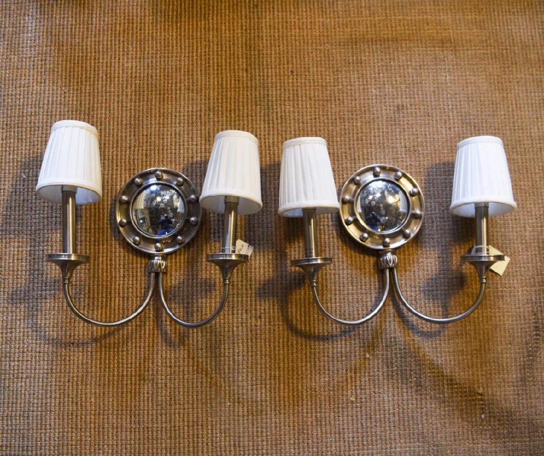 PAIR OF CONTEMPORARY MIRRORED SCONCES: Nickel like finish. Faux bullseye mirror. Two light. Dimensions: H 11" x W 14" x D 4.5" Condition: Uneven arms. Some surface handling.