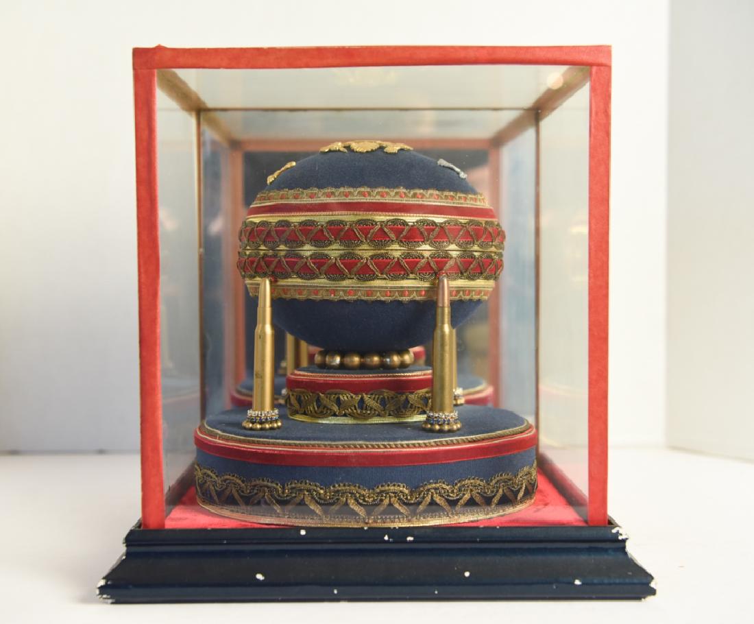 MONUMENTAL DECORATIVE FABERGE EGG REPRODUCTION: Ron Buebendorf. With bullets and military insignia. Opens to reveal a cannon. Dimensions: H 8.5" x W 8.25" x D 7" Condition: Some chips to display case paint finish.