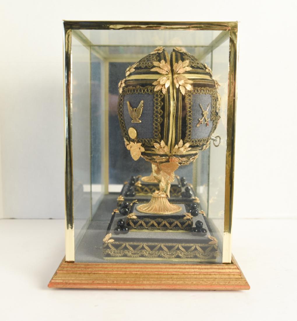 MONUMENTAL DECORATIVE FABERGE EGG REPRODUCTION: Ron Buebendorf. Opens to reveal soldier guarding a door and American flag. Dimensions: H 11.5" x W 6" x D 6" Condition: Some light handling wear to display case.