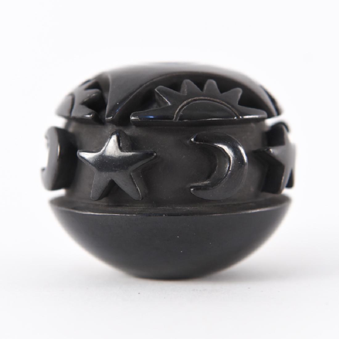 NANCY YOUNGBLOOD (B. 1955): Santa Clara Pueblo carved black pottery seed jar. Carved with sun, moon, and stars. Signed and dated 1983 on base. Dimensions: H 2" x Dia. 2.25" Condition: No issues to note. Provenance: From a Greenw