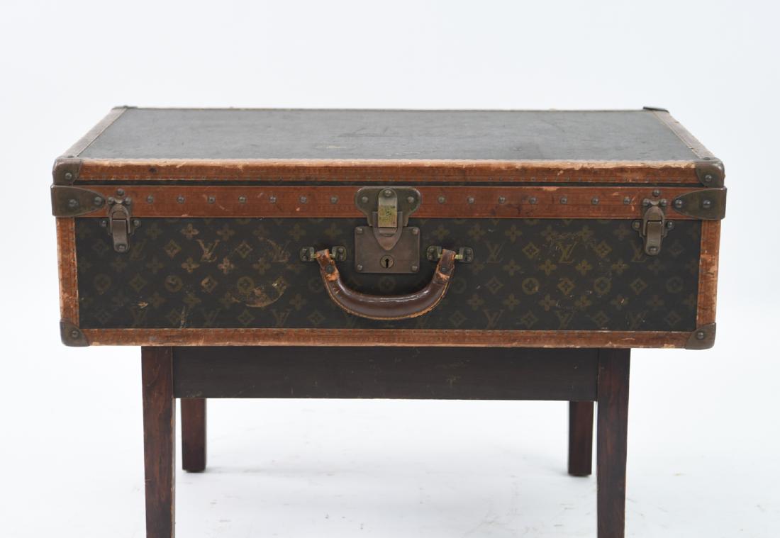 LOUIS VUITTON HARD CASE SUITCASE: Matched with wooden stand. Marked "Louis Vuitton made in France" on hardware and interior. Dimensions: (Suitcase) H 9" x W 30" x D 18" Condition: Leather dry. Some cracks and losses to leather. Scuffs