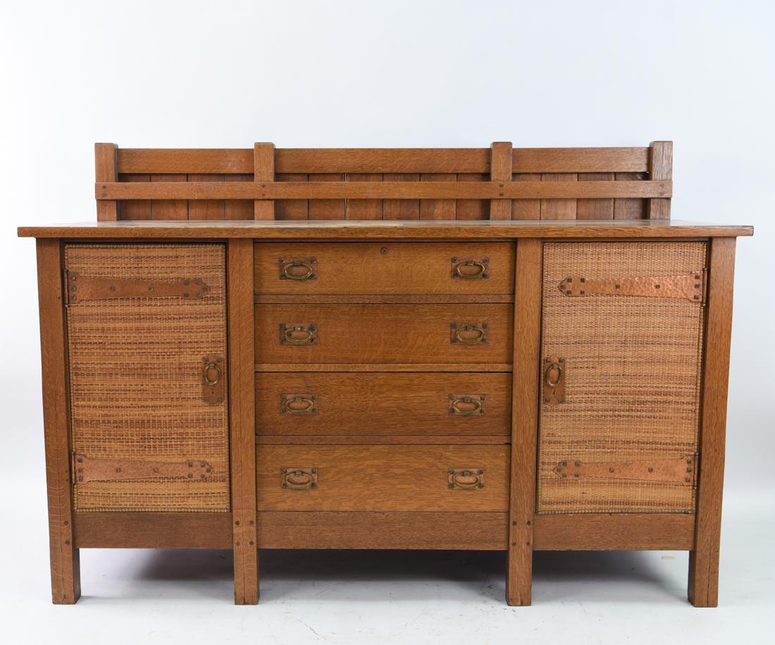GUSTAV STICKLEY 8 LEG MISSION OAK SIDEBOARD: Marked on interior of drawers. Dimensions: H 47.5" x W 70" x D 25.5" Condition: Showing light finish wear. Few scratches and marks. Slight separation of surface boards. Loose and detached trim to door