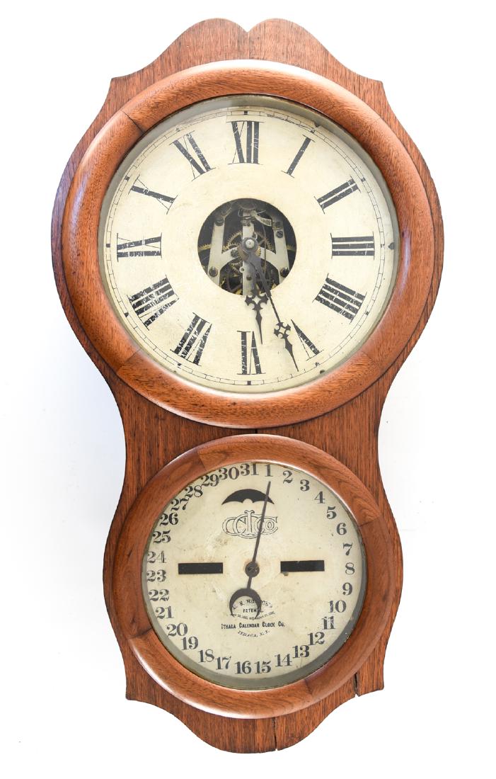 ITHACA CALENDAR CLOCK: Dimensions: H 29" x W 15.5" x D 4.5" Condition: No calendar works; looks to have been restored and reworked. No pendulum. Not tested. Surface wear to faces. Some splits to wood.