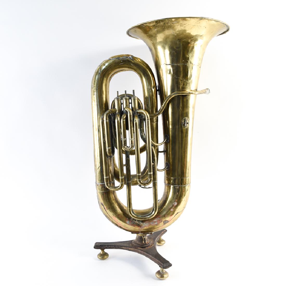 ENGLISH BRASS EUPHONIUM ON STAND: Can be used as planter. Dimensions: H 39.5" x W 23" x D 16.75" Condition: Showing some patina from use as planter. Mouthpiece loose. Surface wear and dents consistent with age throughout.