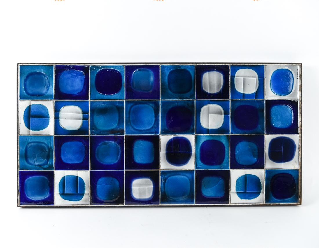 ROGER CAPRON MID-CENTURY MOSAIC TILE ART: Signed to corner. having mounting screws on the back for wall mount or for table legs. Dimensions: H 1.5" x W 32" x D 16.25" Condition: Some rusting. Showing wear consistent with age and use.