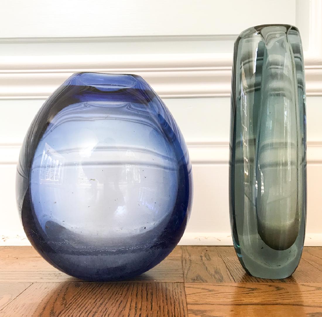HOLMEGAARD ART GLASS VASE GROUPING: Both signed on base. Dimensions: (Blue) H 9.75" x W 7.5" x D 6.5" Condition: Showing handling wear including a few small surface nicks to blue glass. Couple light scratches.