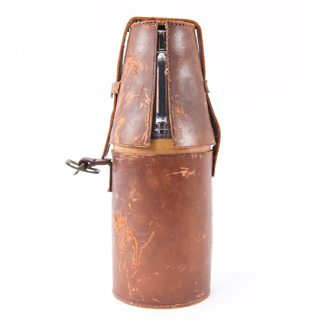 LEATHER TRAVELING BAR: Leather holder with martini shaker, shot glasses, decanters, etc. Dimensions: H 12" x Dia 5" Condition: Missing one decanter, top present, wear to leather, signs of use.
