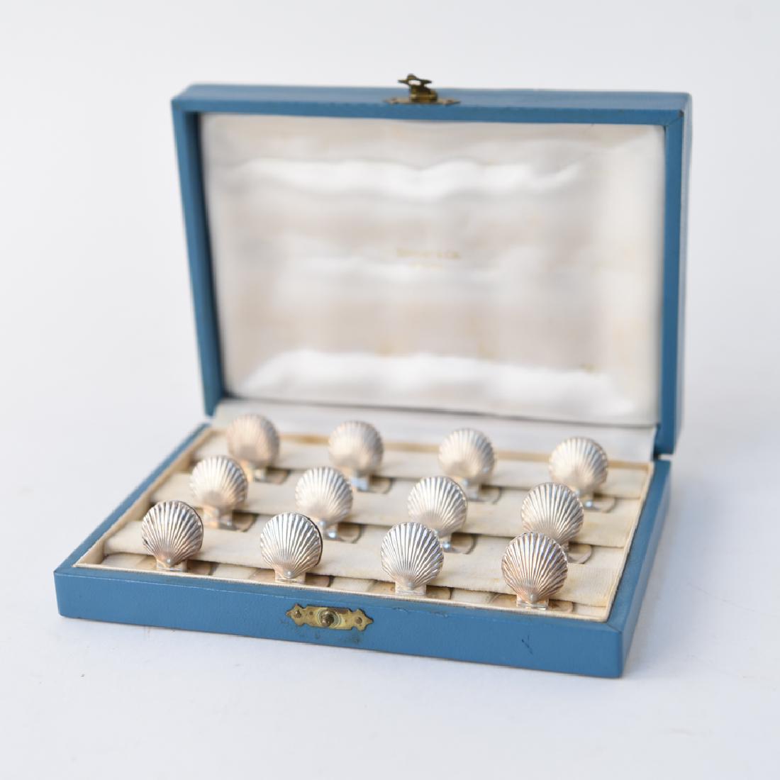TIFFANY STERLING SILVER SHELL PLACECARD HOLDERS: A complete set of 12, sterling silver Tiffany & Co. place card holders. Hallmarked on bottom and in original box. Dimensions: H .075" Condition: Showing only light signs of age.