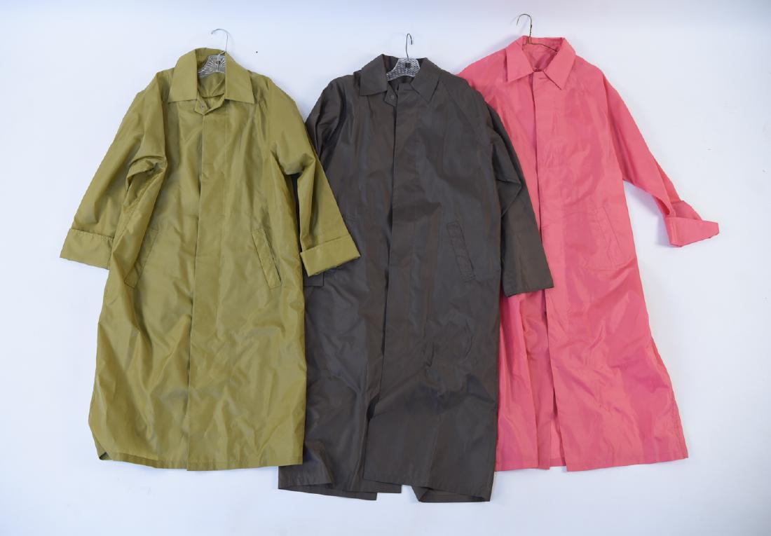 (3) LADIES LONGCHAMP FULL LENGTH RAIN COATS: Full length rain coat or windbreaker. 100% nylon. Included in this grouping are 3 coats, pink, brown and green. Size: Small Condition: Used, with no obvious signs of use.