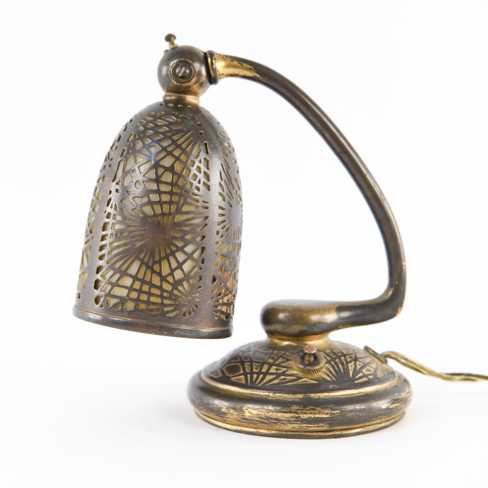 TIFFANY STUDIOS PINE NEEDLE PIANO LAMP: Marked underneath: Tiffany Studios New York 552. Bronze and slag glass Dimensions: H 7.5" x W 5.75" x D 4" Condition: Some flea bites to slag glass panel edges shown on interior of shade. Some patina.