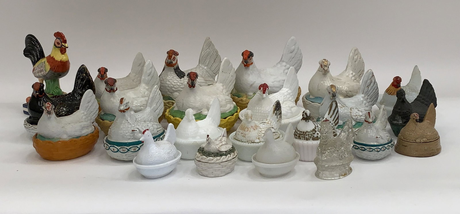 LARGE GROUPING OF GLASS AND CERAMIC HENS: Count: 23. Incl. Staffordshire. Including one cast metal. Dimensions: (Largest) H 7.75" x W 10.5" x D 7.25" Condition: Light surface dirt, handling wear, some paint loss. Couple chips. Some with crazi