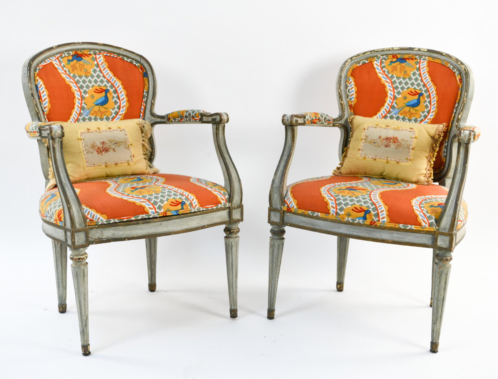 PAIR OF 18TH C. FRENCH STYLE FAUTEUIL CHAIRS: Faux antique painted. With vibrant upholstery. Accompanied by throw pillows with aubusson tapestry. Dimensions: H 35.5" x W 24" x D 22" x SH 18.5" Condition: Some joint separation and paint loss.