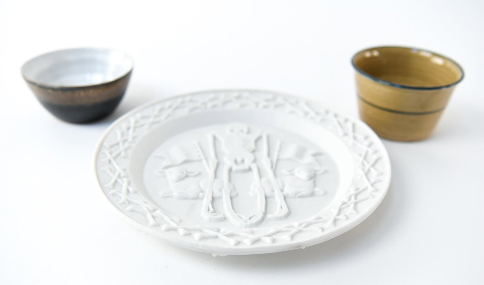 DECORATIVE CERAMIC GROUPING: (3) pieces. Including: Studio Job Biscuit series plate "Innocence," marked underneath. Two small pottery bowls, signed underneath. Dimensions: (Plate) Dia. 9" Condition: Light surface dirt to plate.