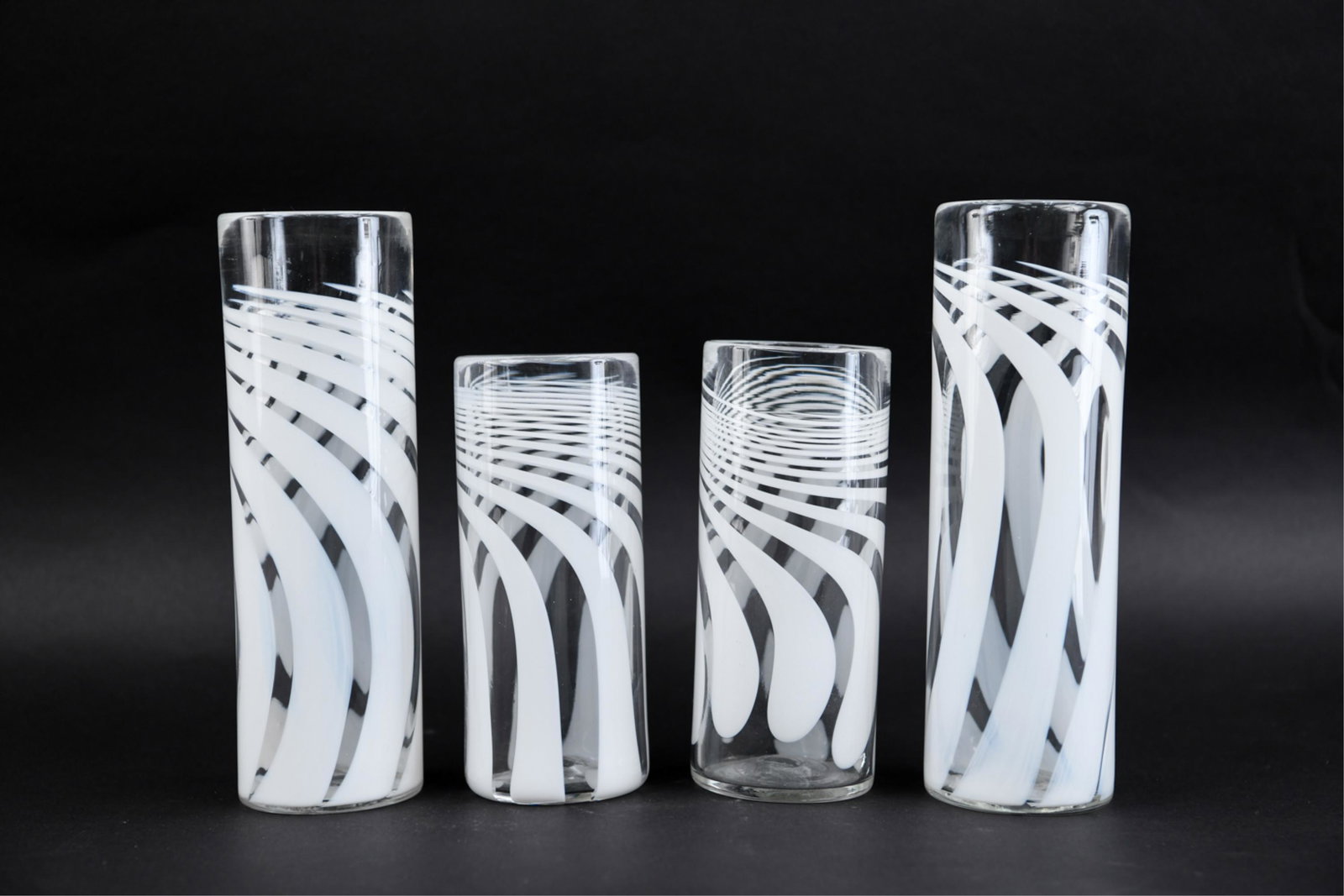 (4) ANTHONY STEARN SWIRL GLASS CYLINDER VASES: Anthony Stearn, British. White and clear swirl art glass. Dimensions: (Taller) H 10" x Dia. 3.25" Condition: No issues to note.