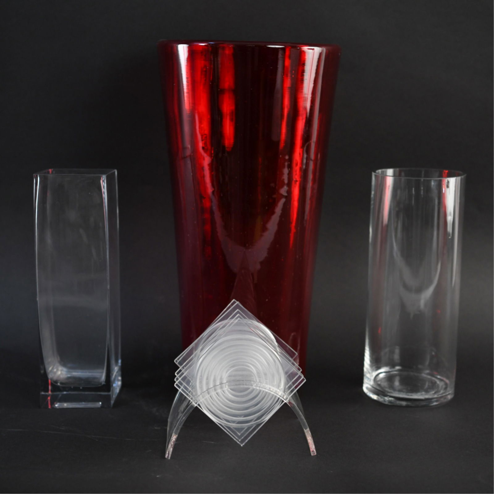 MODERN GLASS GROUPING: Red vase hand blown with pontil base, other two vases molded. Including three vases and coaster set. Dimensions: (Largest) H 15.5" x Dia. 7.75" Condition: Minor surface scratches, coaster set has one