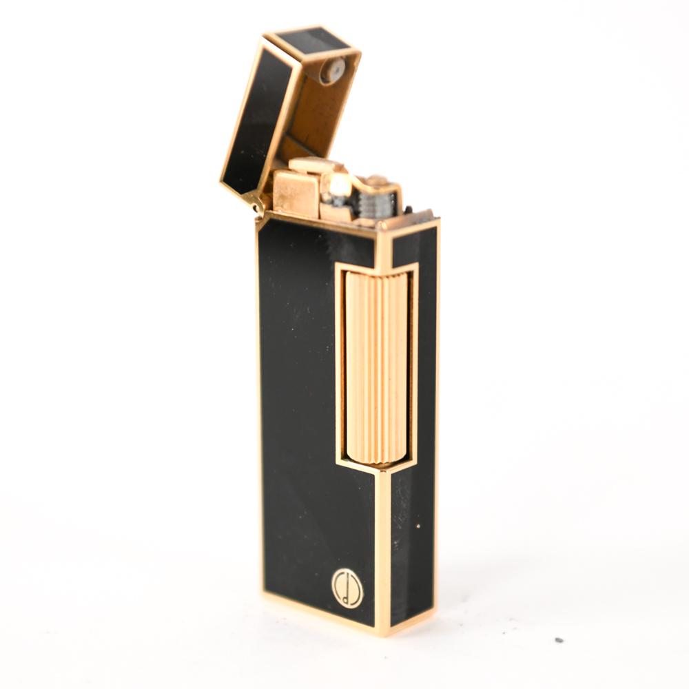 DUNHILL ROLLAGAS LIGHTER IN BOX: Gold plated and black lacquer. Fully marked: Made in Switzerland and patent number USRA24163. Dimensions: (Lighter) H 2.5" x W 1" Condition: Non-functional. Spit in metal where flint goes.