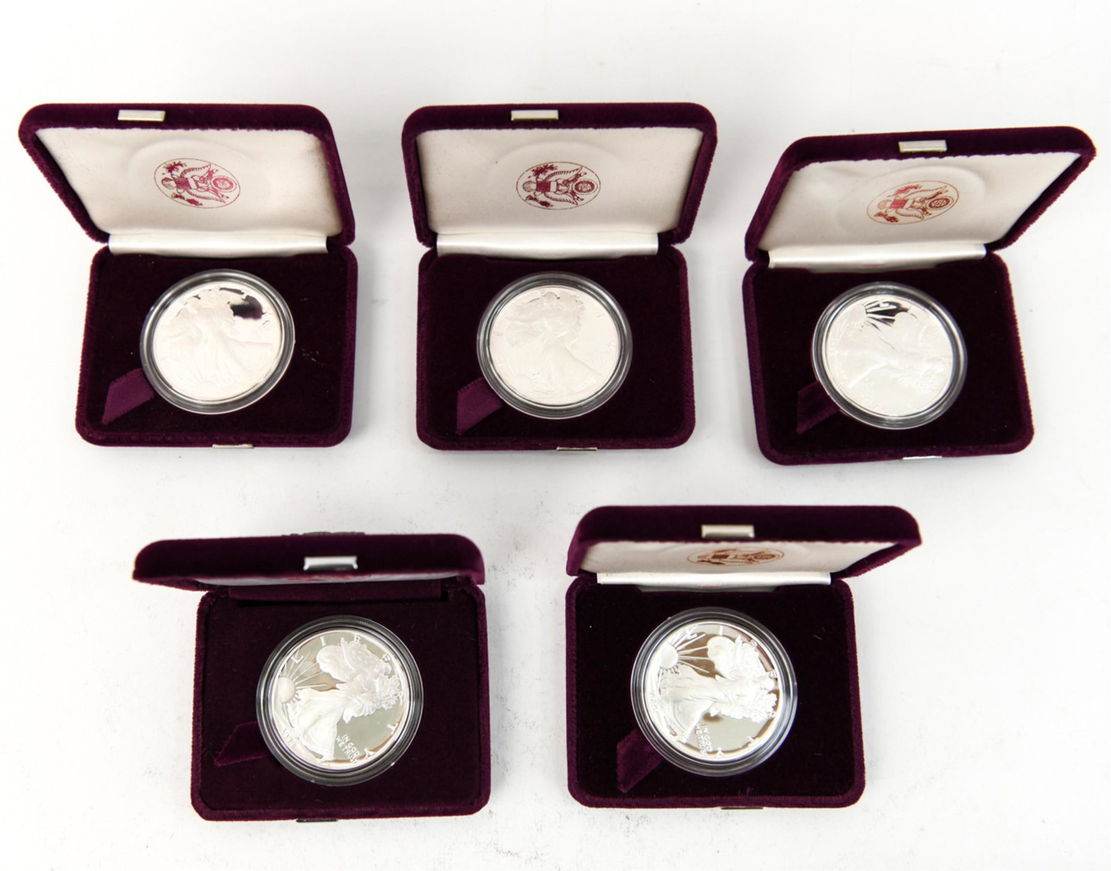 GROUPING OF AMERICAN EAGLE SILVER PROOF COINS: (5) American Eagle silver bullion proof coins in cases. Years includes (2) 1988, (2) 1986, (1) 1990. Each coin weighing one ounce. Condition: As shown, minor handling signs to boxes.