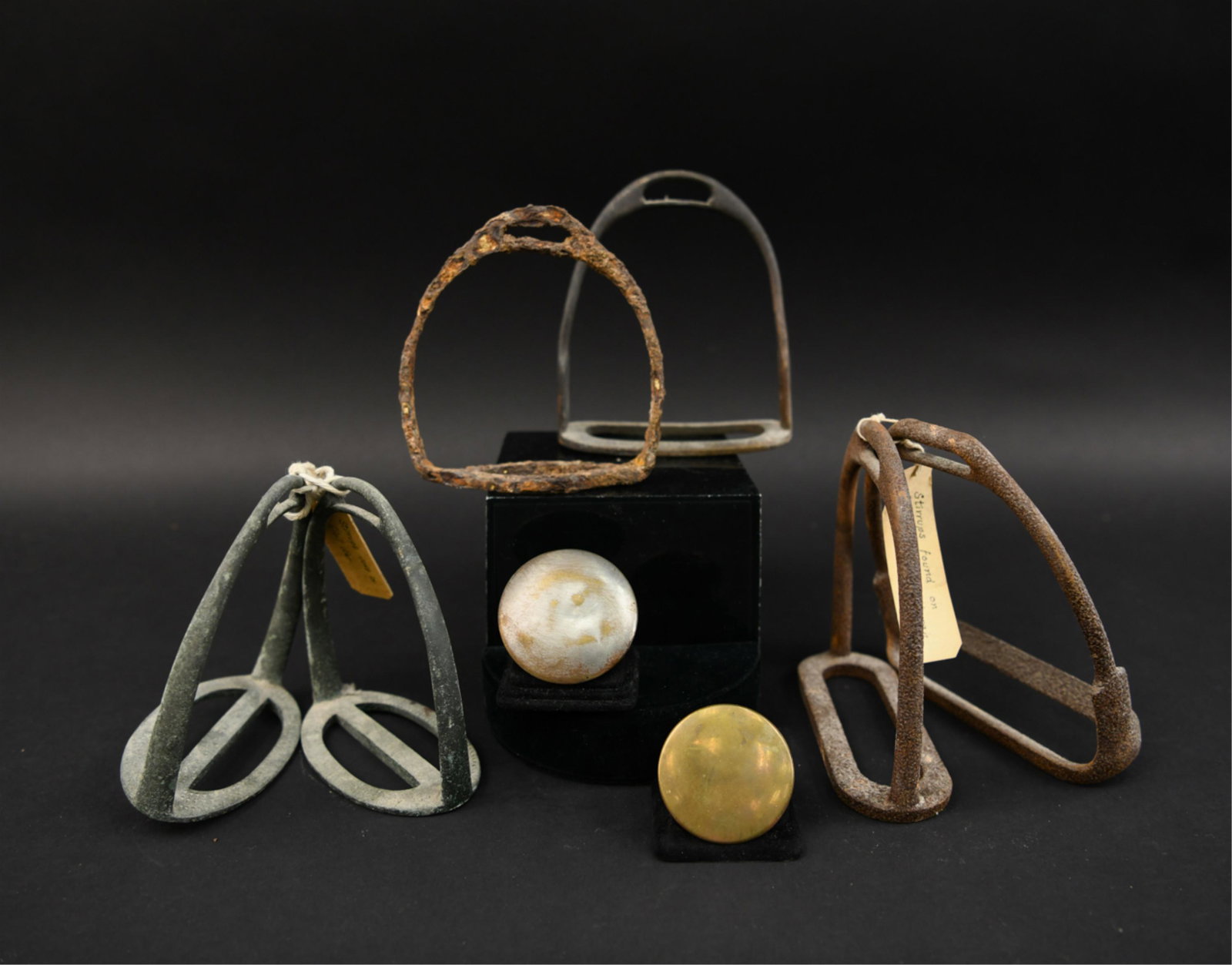 19TH C. CIVIL WAR ERA EQUINE ACCOUTREMENTS: (8) pieces. Including (6) stirrups and (2) rosettes. Most with tags from collector for Gettysburg Battlefield. Dimensions: (Stirrup) H 6" Condition: As found.