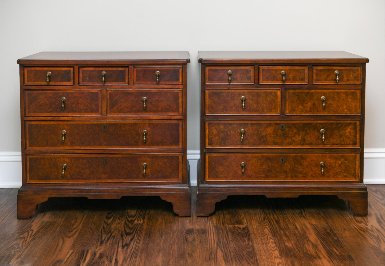 PAIR OF BAKER GEORGIAN STYLE CHESTS: Three over two over two drawer. Burl wood with banded inlay. Brass pulls. Dimensions: H 32" x W 18" x D 34" Condition: Some edge wear and surface wear. Side of one with water damage.