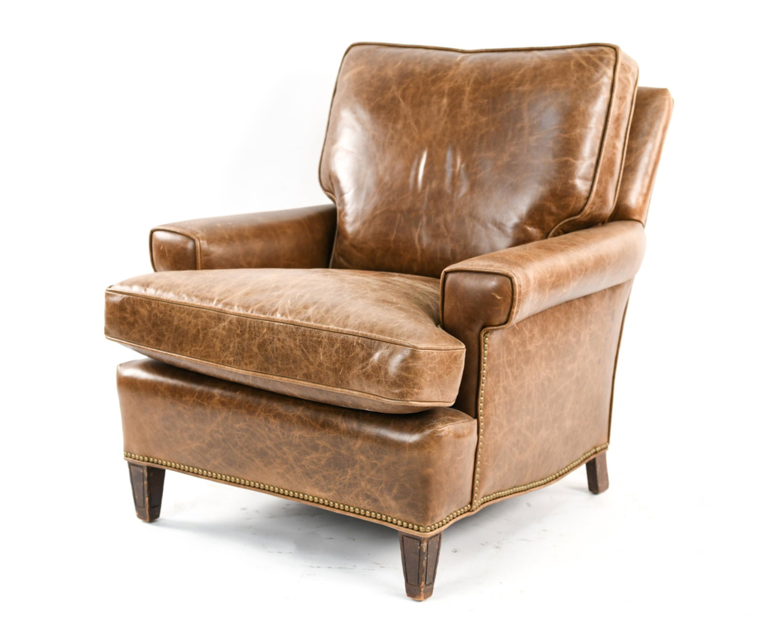 LEATHER CLUB CHAIR: Brown leather with brass tacks. Dimensions: H 35" x W 33" x D 39" x SH 20" Condition: Scuffs to leather, fading to leather.