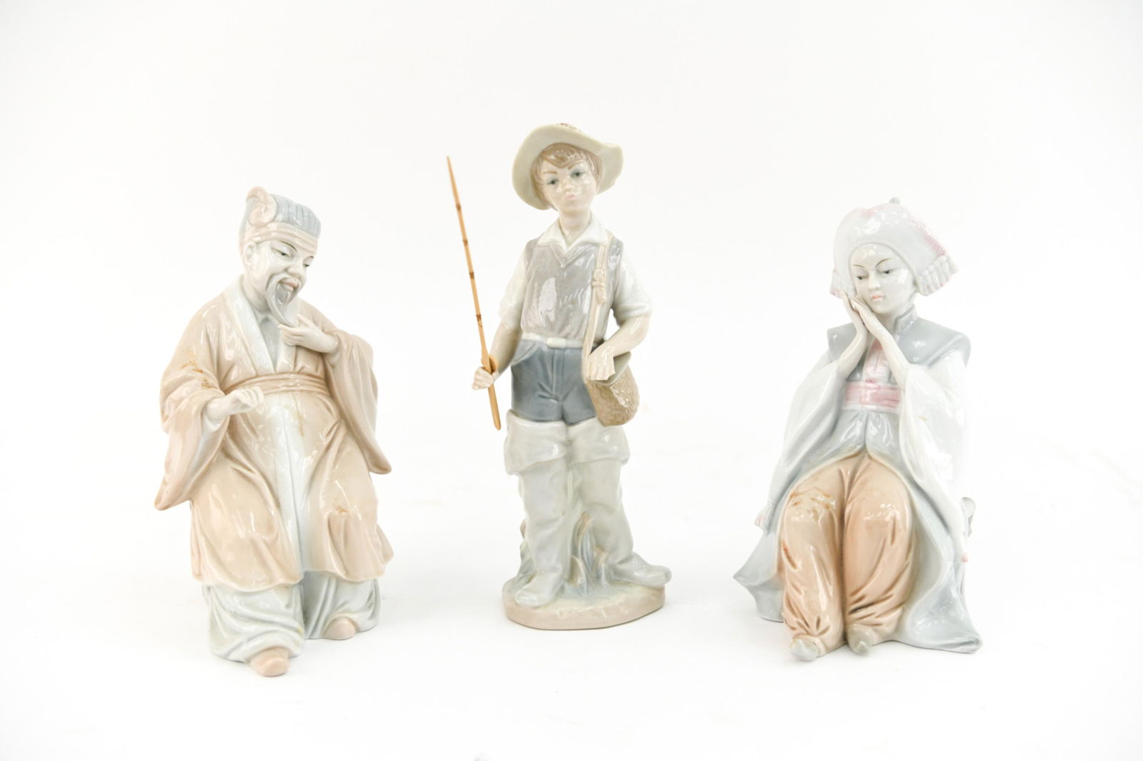 (3) PORCELAIN FIGURES: Including KPM and Lladro. Lladro of young fisherman, KPM pair of seated Asian figures. Dimensions: (Tallest) H 8.75" x W 3.25" x D 2.5" Condition: Showing light handling wear including a small chip to