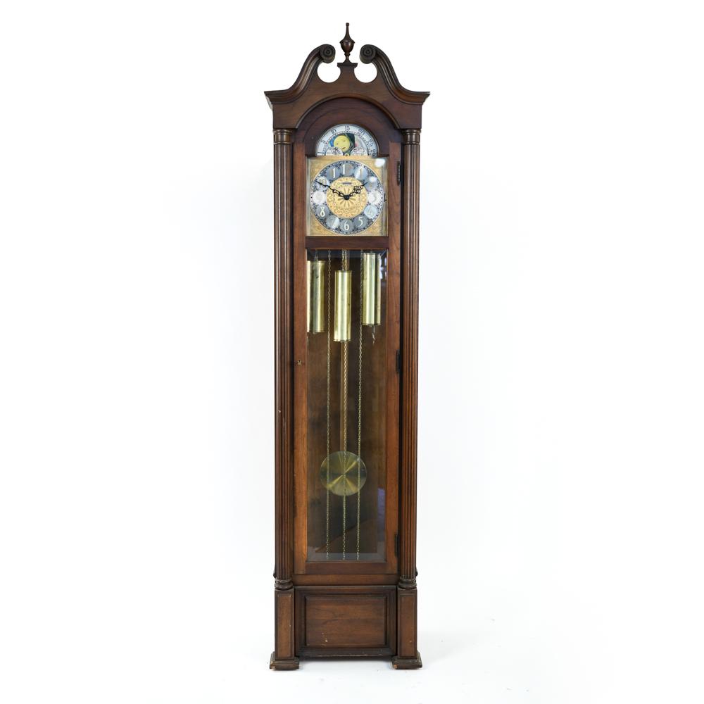HOWARD MILLER TALL CASE CLOCK: Label on back. With door key. Including weights, pendulum. Dimensions: H 82.5" x W 22.25" x D 15" Condition: Not tested. One upper side panel missing/broken. Nicks and scratches.