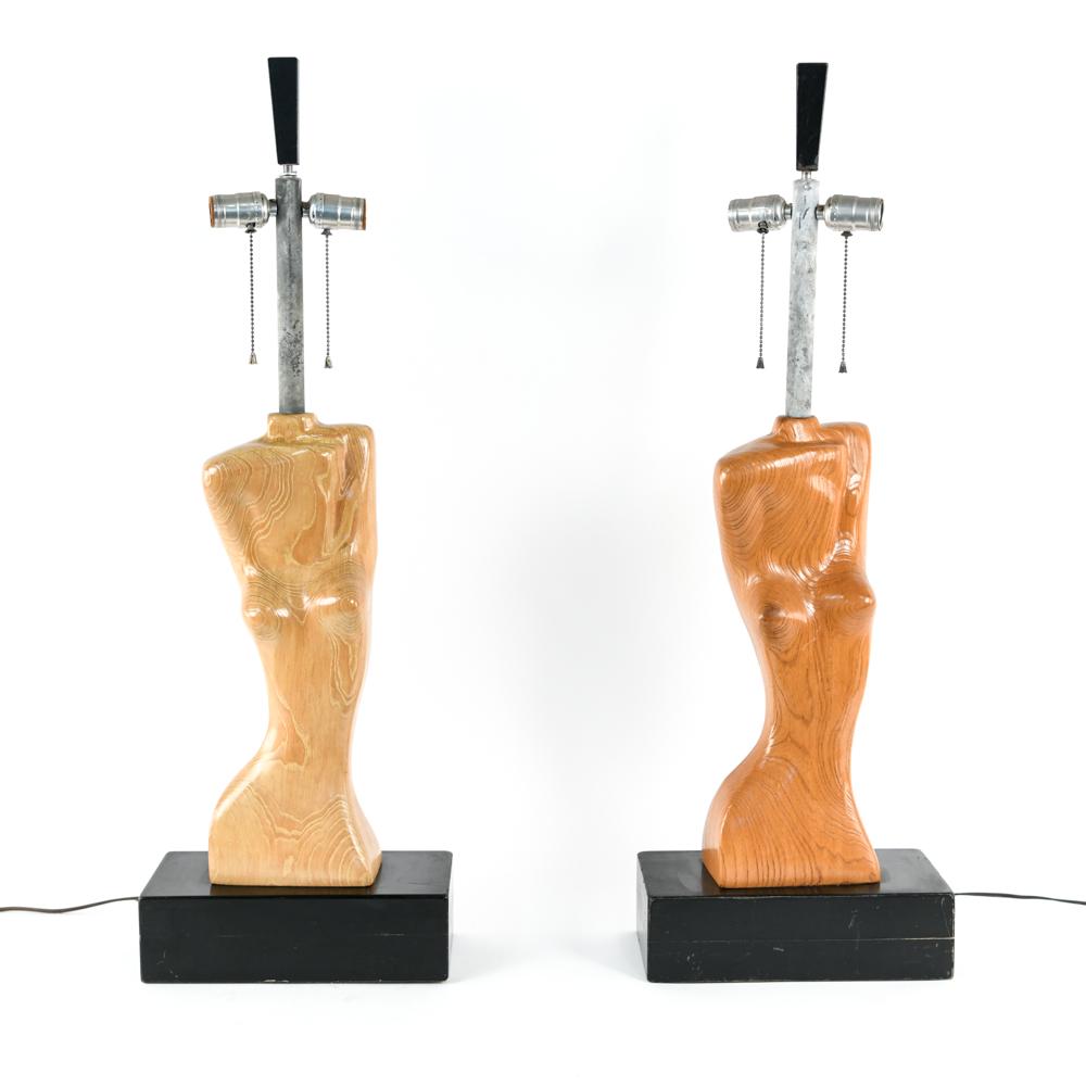 PAIR OF HEIFETZ CARVED WOOD NUDE FORM LAMPS: Dimensions: H 35.25" (top of finial) x W 12" x D 6" Condition: Untested. Wear consistent with age and use including scratches, chips and scuffs to wood and bases. Patina to metal. One has a little dar