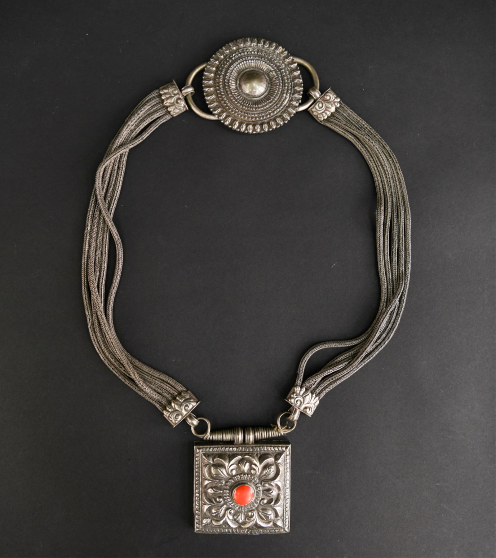 TIBETAN SILVER & CORAL AMULET NECKLACE: Berber silver with central stone. Dimensions: L 19.5" x W 3.5" (square amulet) Condition: Wearable, showing signs of age and use.
