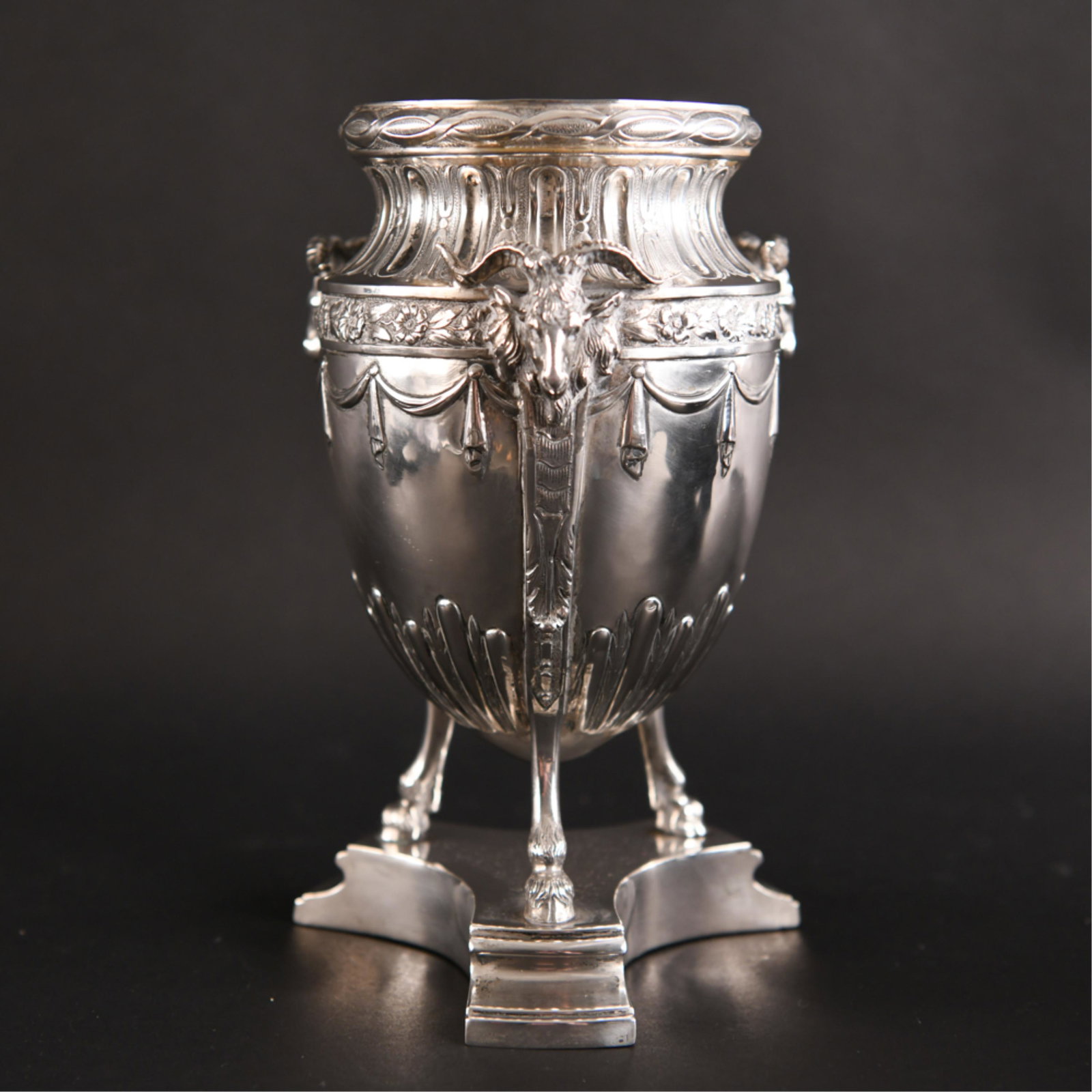 19TH C. SILVER URN W/ RAMS HEADS: Highly decorated with ram heads, swag, floral and foliage and three hoofed base. Bearing partially stamped hallmark under as well as another hallmark along the edge. Dimensions: H 9.5" x Dia: 5.5" Wei