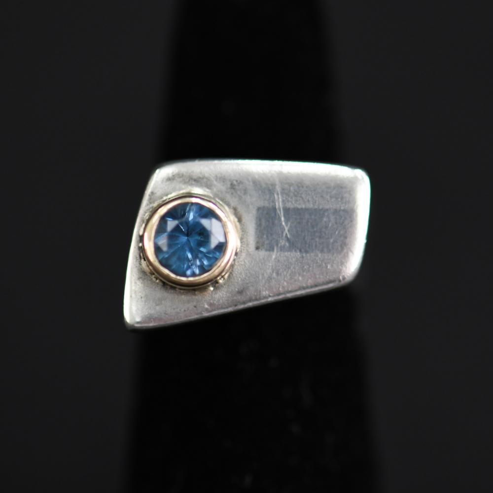 STERLING SILVER, GOLD, & TOPAZ MODERNIST RING: No visible hallmarks, sterling silver and 14k gold with a small blue topaz stone. Dimensions: Face: 0.75" Ring Size: 6 Condition: Showing light signs of use and age.