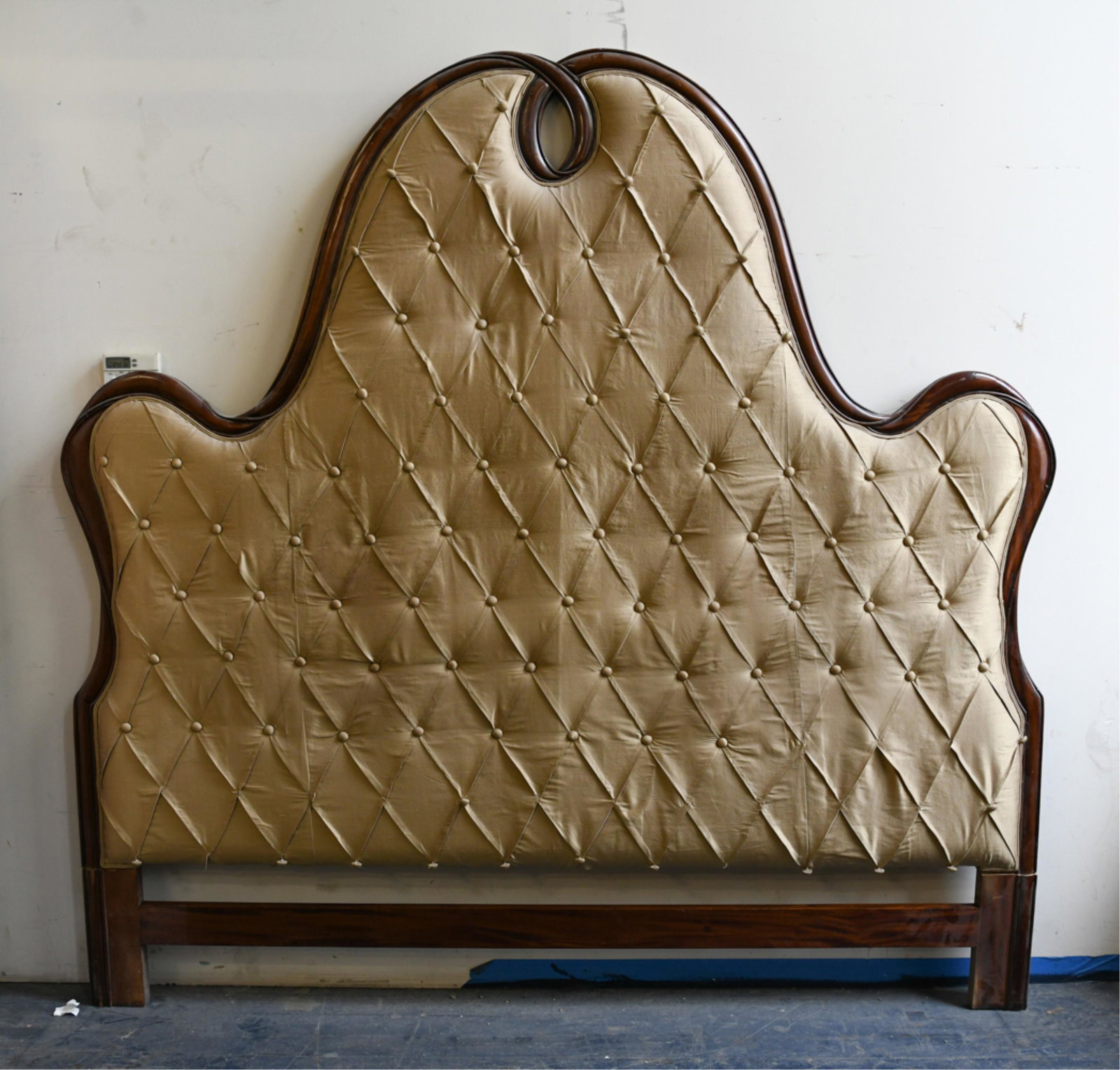 KING-SIZE SILK AND MAHOGANY TUFTED HEADBOARD: Dimensions: H 70" x W 85" x D 3" Condition: Feet have been cut to fit into a room at one time, can be reattached. Some buttons loose. Light fraying to fabric. Few dings to wood border.