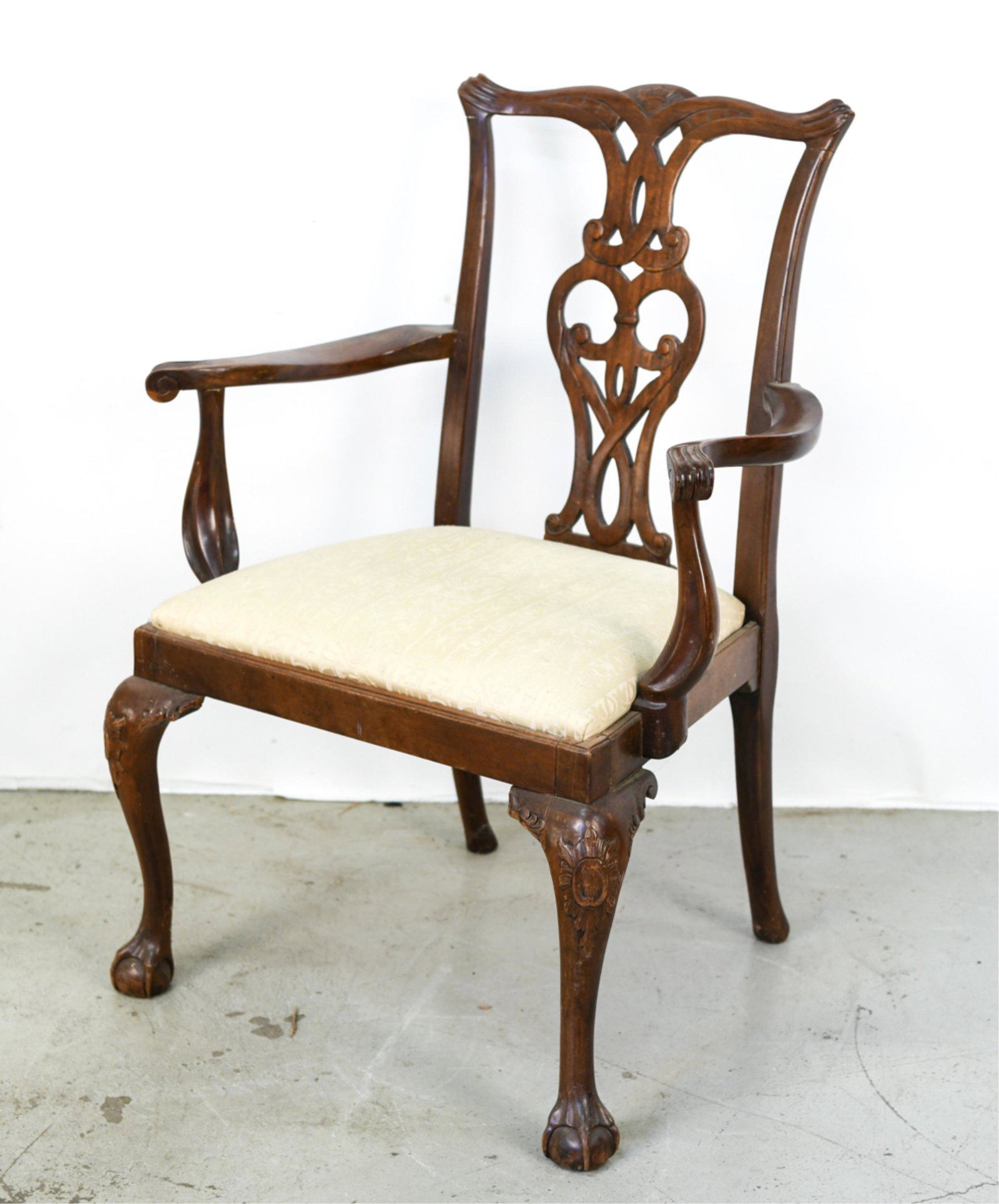 ANTIQUE CARVED CHIPPENDALE STYLE ARMCHAIR: Carved back splat, ball and claw feet. Dimensions: H 38.25" x W 28" x D 20" x SH 18" Condition: Cracks to front right corner. Signs of use and age including scratching and scuffing.