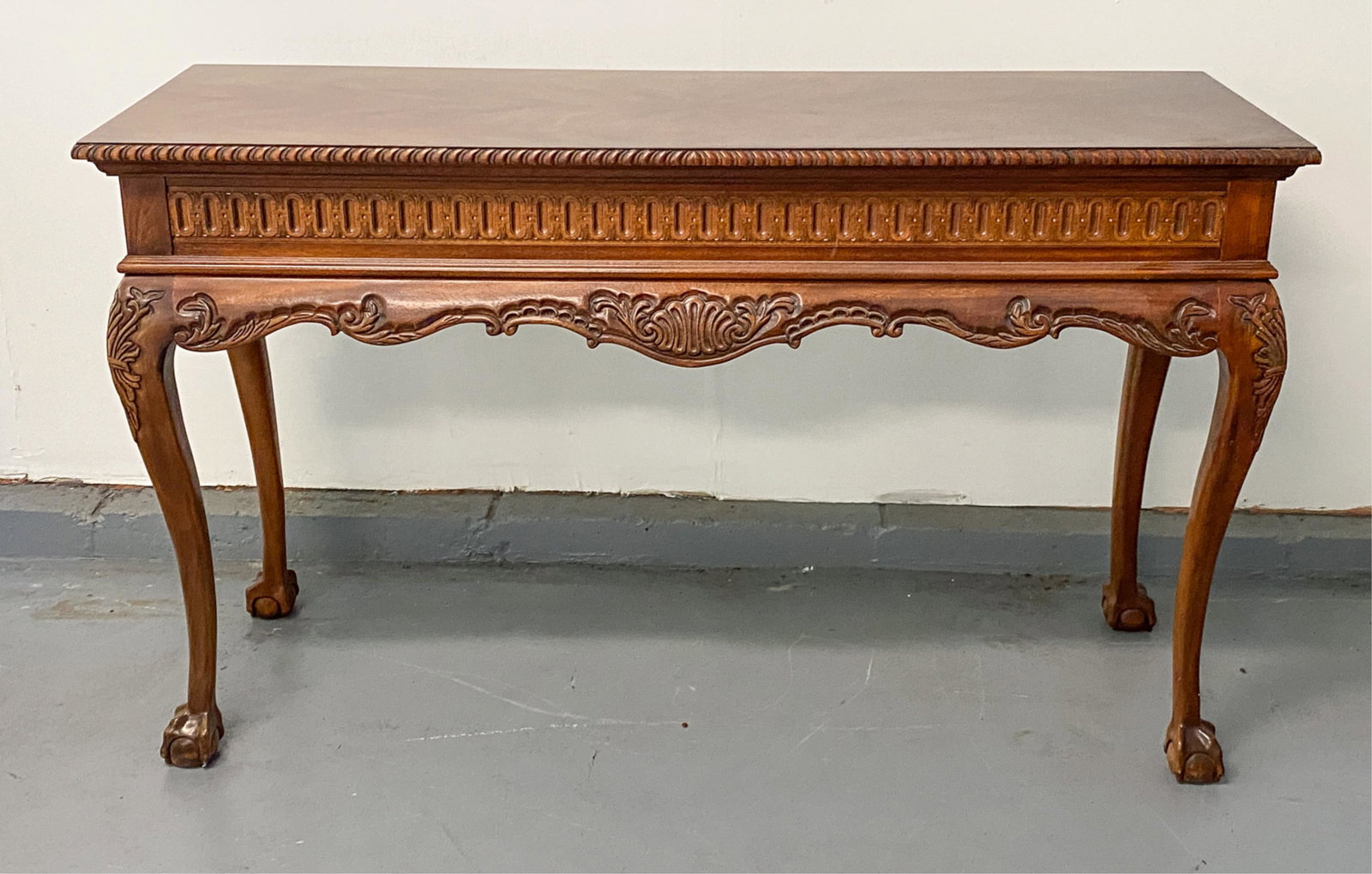 CARVED WOOD CONSOLE TABLE: Carved. Claw and ball feet. Dimensions: H 31.25" x W 51.75" x D 18" Condition: Some fading and finish wear. Surface scratches and scuffs to top.