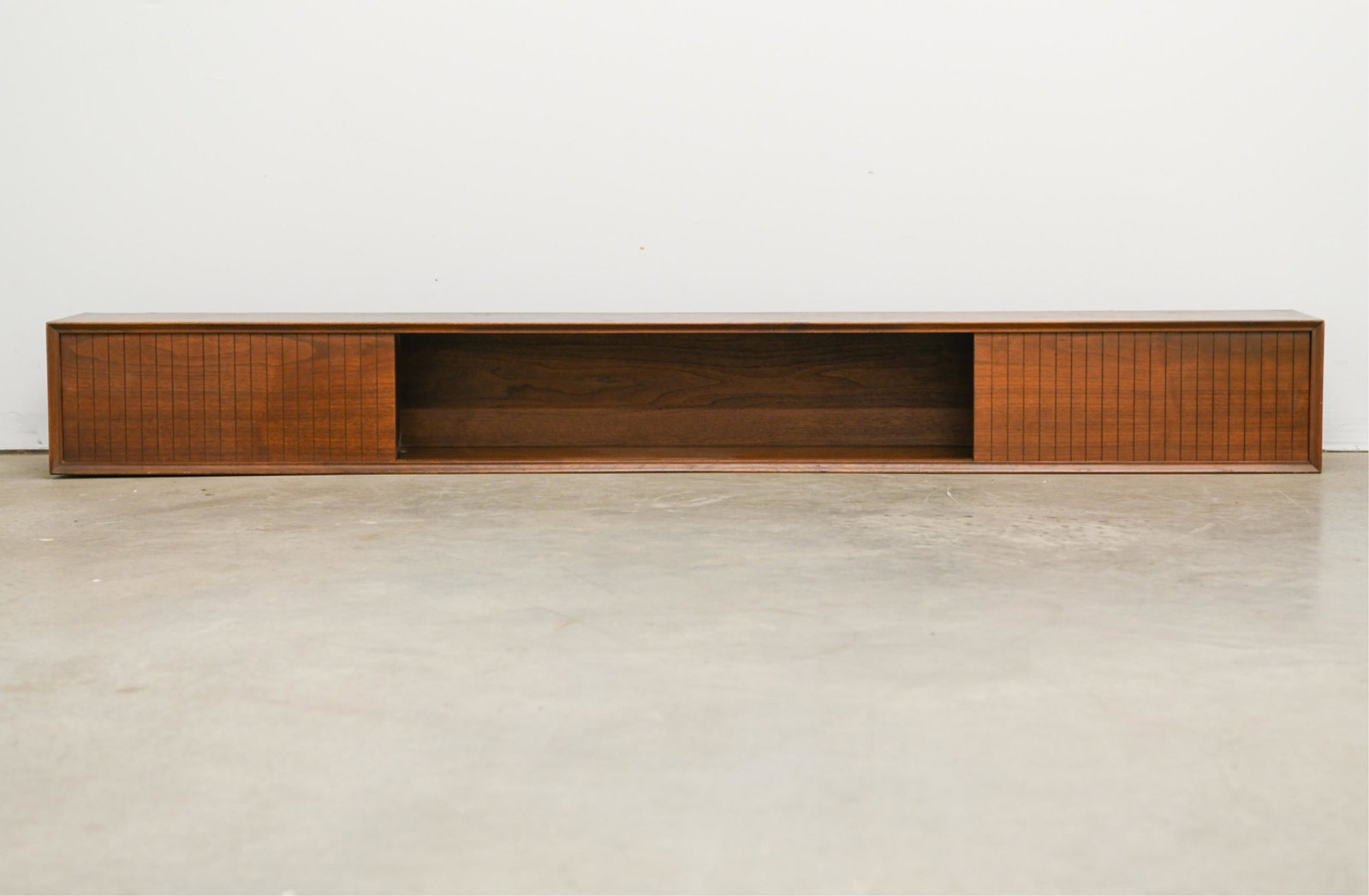 MID-CENTURY WALL CABINET SHELF W/ SLIDING DOORS: Dimensions: H 10" x W 82.5" x D 10" Condition: Some losses to the veneer.