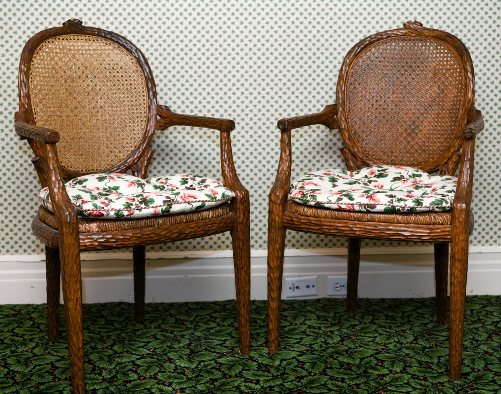 PAIR OF CARVED ARMCHAIRS: Rush seats, floral seat cushions, caned backs. Dimensions: H 38.75" x W 22.5" x D 24" x SH 21" Condition: Some wear to rush seats. Light wear consistent with use.