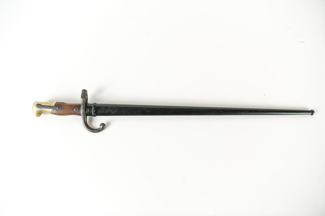 1889 BAYONET: With inscription along edge. Serial no. 67677, same on scabbard and bayonet. Dimensions: L 26" x W 4" x D 1" Condition: Very slight surface wear on the blade.