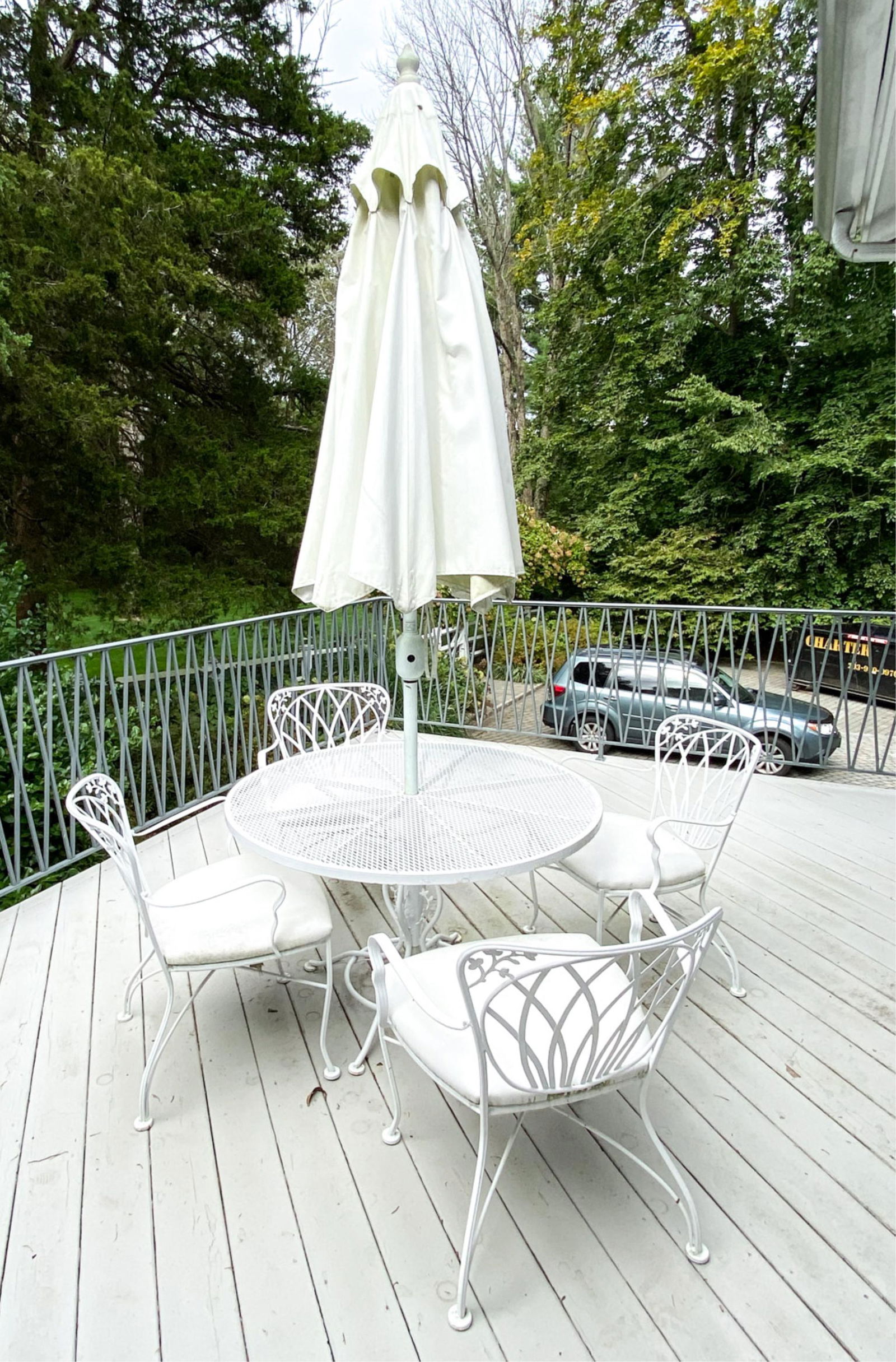 IRON OUTDOOR TABLE AND CHAIR SUITE: Dimensions: (table) H 25.5" x Dia. 42" Condition: Wear consistent with outdoor use, including surface dirt and slight pitting and rust to the metal on chairs. Cracking on paint on the table, umbrella