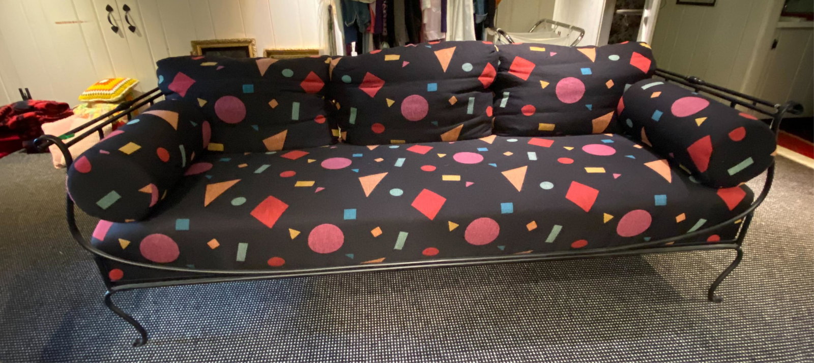 IRON SOFA DAYBED: Black painted scrolling metal with abstract patterned upholstery Dimensions: H 28" x W 82" x D 34" SH 19" Condition: Slight wear to the upholstery