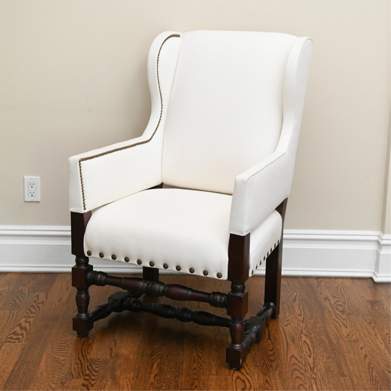 CONTEMPORARY BAROQUE STYLE CHAIR: Wing chair with brass tacked upholstery and turned legs Dimensions: H 43" x W 26.75" x D 33" SH 19" Condition: Very slight wear to the corners of the arms and a few nicks to the corners of legs