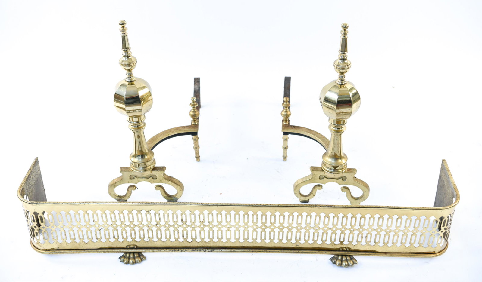 BRASS FIRE FENDER AND ANDIRONS: Dimensions: (Fender) H 8.25" x W 47.5" x D 9" Condition: Wear consistent with age and fireplace use including patina to metal with minor dents.