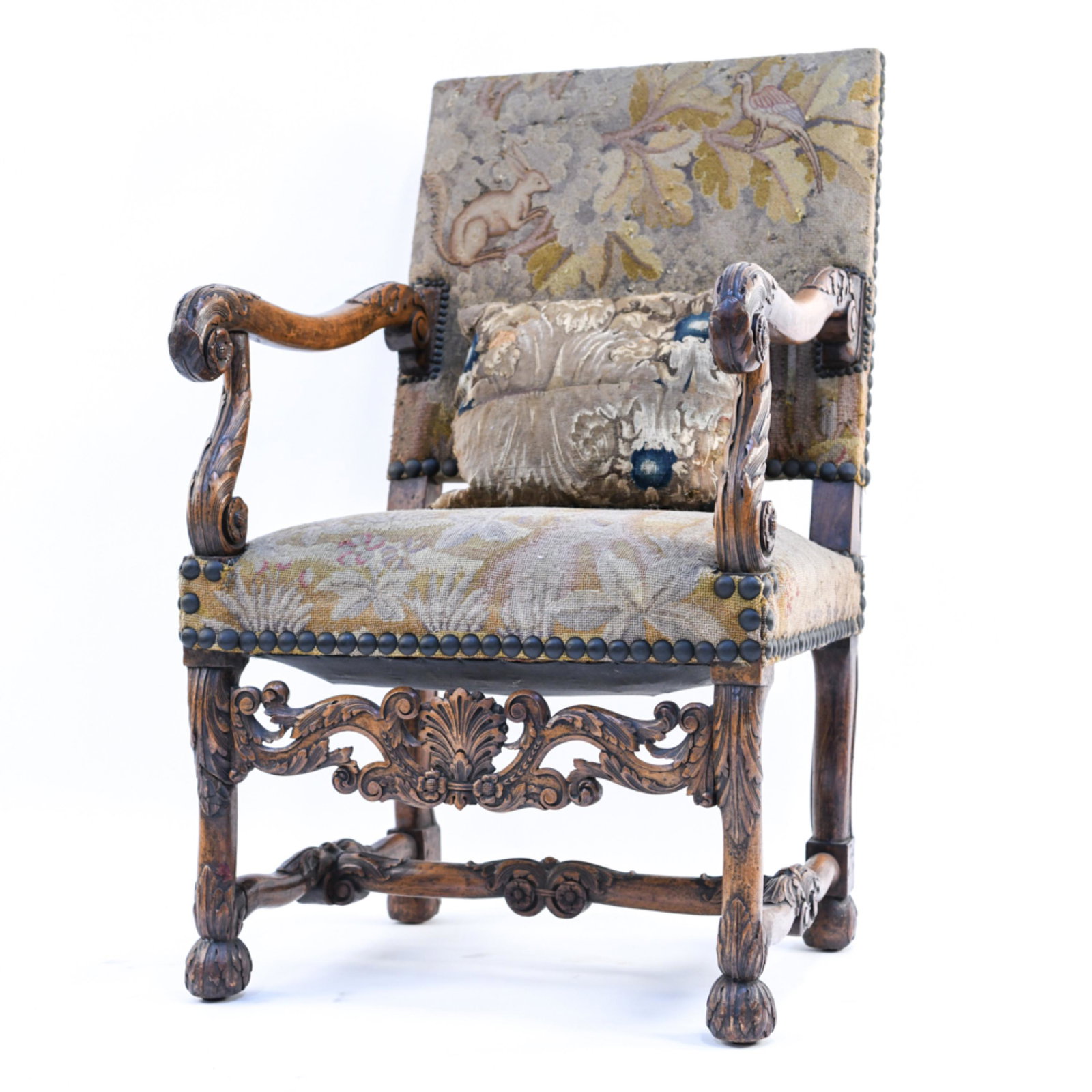 CARVED FLEMISH EMBROIDERED ARMCHAIR: With medieval style floral and animal needlepoint upholstery and nailhead edge trim. Dimensions: H 43" x W 23.5" x D 28" x SH 20" Condition: Wear consistent with age and use including nicks and finish