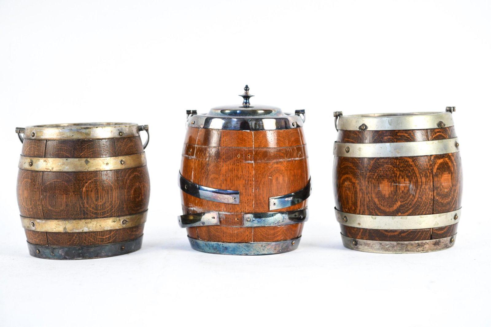 ENGLISH SILVERPLATED WHISKEY BARREL BISCUIT JARS: Ceramic interiors. (3) pieces. Dimensions: (Including handle) H 11" x Dia. 6" Condition: Two without lid. Banding separating. Tarnish.
