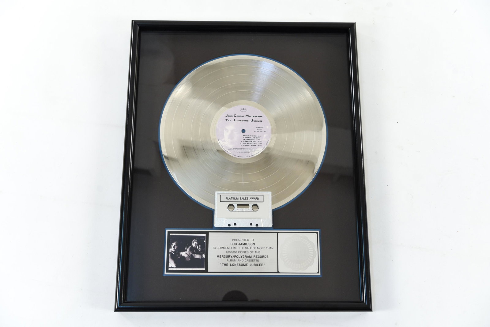 PLATINUM SALES AWARD JOHN COUGAR MELLENCAMP: "The Lonesome Jubilee." Presented to Bob Jamieson. RIAA Certified Platinum Sales Award. Dimensions: (Frame) H 21" x W 17" Condition: Light wear to frame.